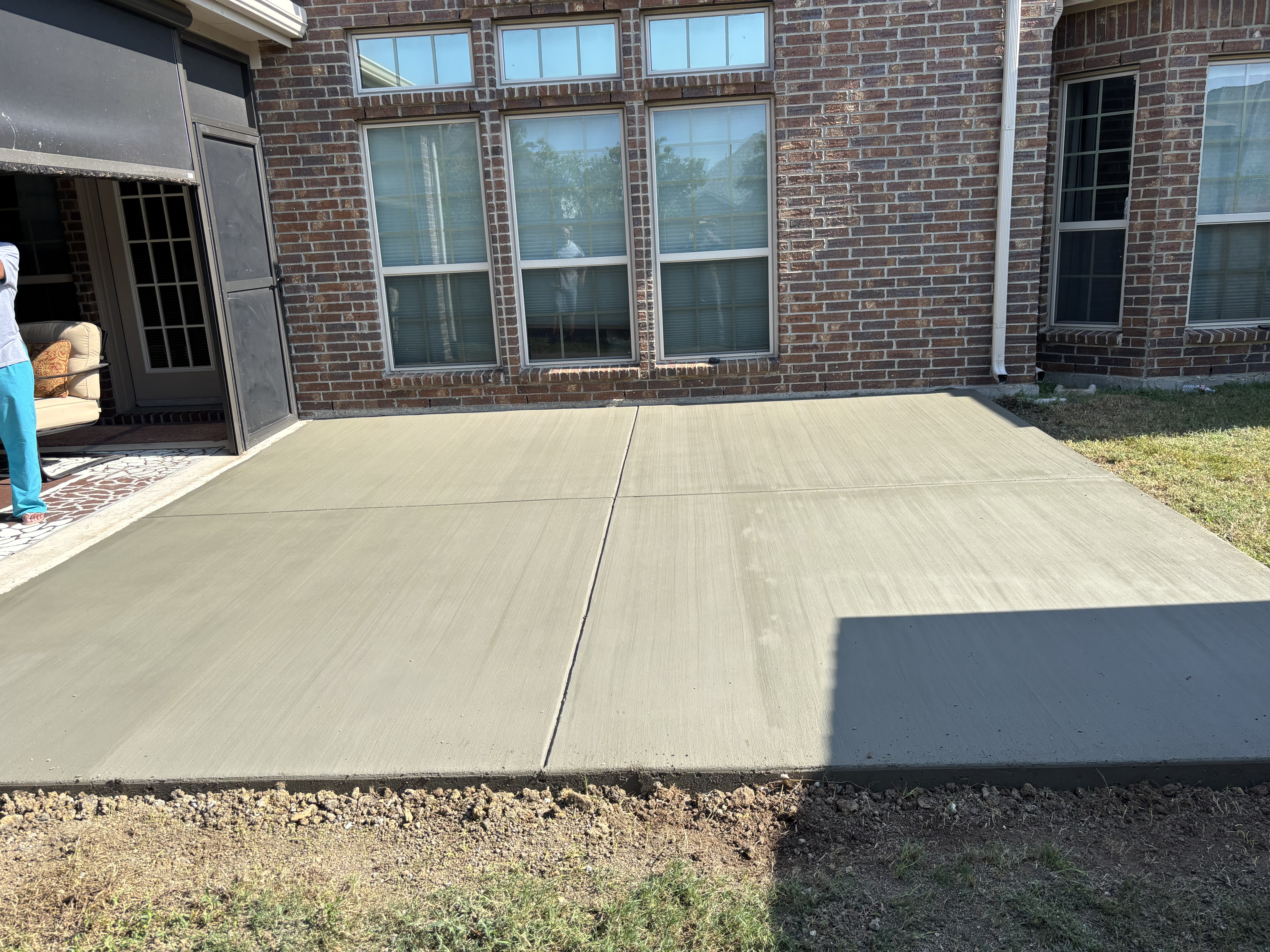 New concrete patio installed behind a brick home